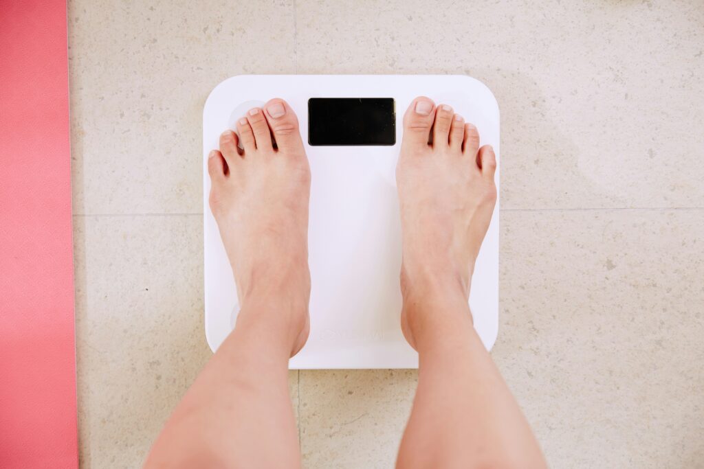 Person standing on a smart scale, symbolizing health data tracking through wellness apps like Noom.