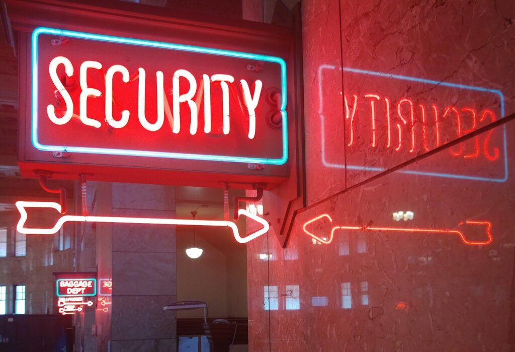 Neon “SECURITY” sign with arrows, symbolizing defense against phishing and other online pests.