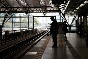 Silhouetted commuters waiting on a train platform, symbolizing the frustration of waiting for missing two-factor authentication codes.