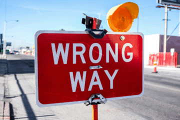 "Bright red 'Wrong Way' road sign with warning light — symbolizing danger and password system vulnerability"