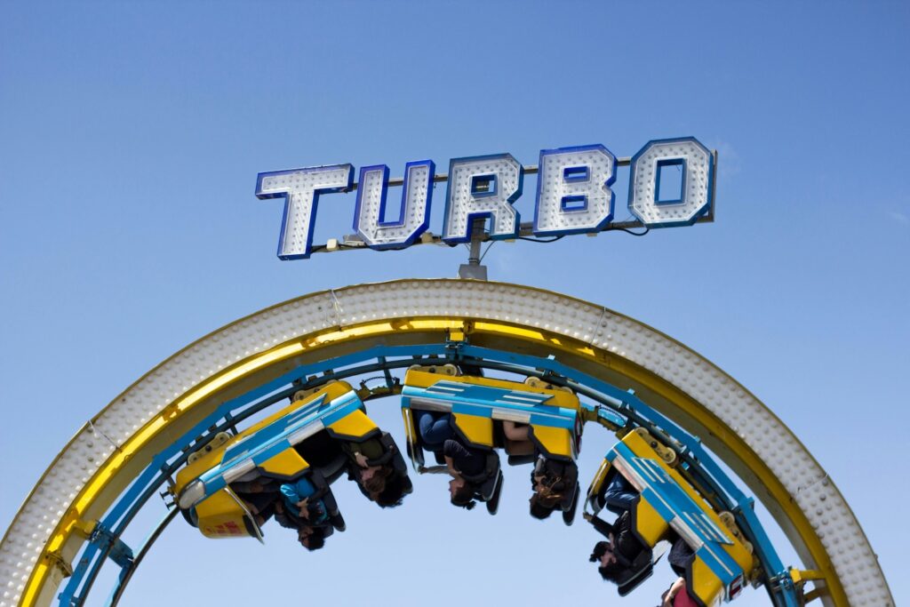 Roller coaster riders in a full loop under a sign reading 'Turbo,' symbolizing the fast and thrilling journey of understanding AI agents.
