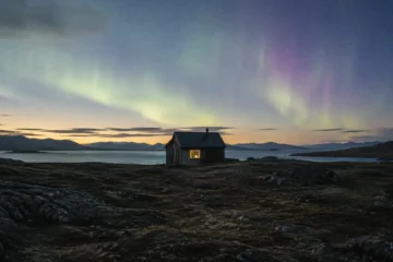 Local Hero-inspired lone research cabin glowing under the aurora, laptop light barely visible in the window — a quiet AI chatbot built to say "I don't know"